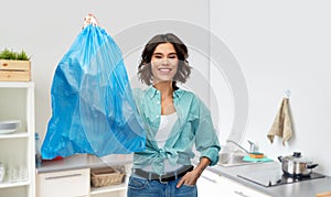 Smiling woman holding plastic trash bag with waste