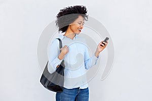 Smiling woman holding purse and mobile phone against gray background