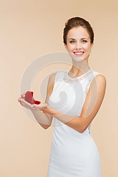 Smiling woman holding red gift box with ring