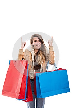 Smiling woman holding shopping bags and pointing up