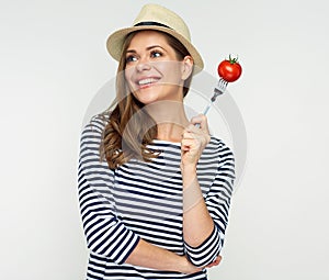 Smiling woman holding tomato on fork.