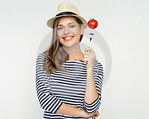 Smiling woman holding tomato on fork.