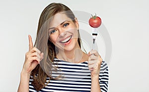 Smiling woman holding tomato on fork.