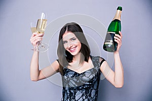 Smiling woman holding two glass and bottle of champagne
