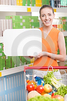 Smiling woman holding a white sign at supermarket