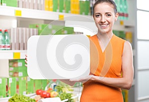 Smiling woman holding a white sign at supermarket