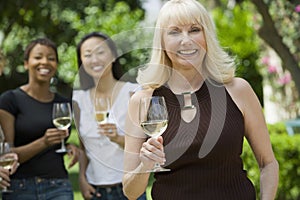 Smiling Woman Holding Wineglass With Friends In Background