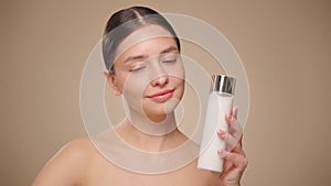 Smiling woman holds bottle with cosmetic milk