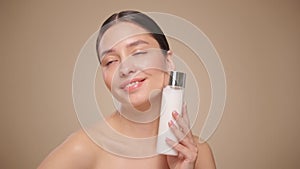 Smiling woman holds bottle with cosmetic milk