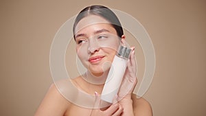 Smiling woman holds bottle with cosmetic milk