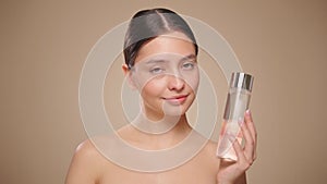 Smiling woman holds bottle with cosmetic tonic