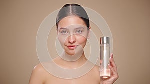 Smiling woman holds bottle with cosmetic tonic