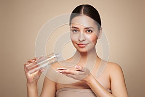 Smiling woman holds bottle with cosmetic tonic photo
