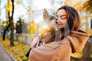 Smiling woman holds in her hands a cute little dog breed biewer terrier and hugs with a smile on his face on the background of