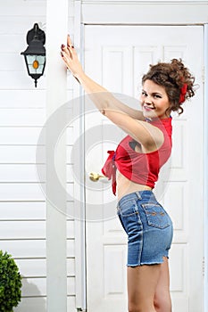 Smiling woman holds pole next to white entrance door