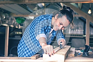 Smiling woman in a home workshop measuring tape measure a wooden Board before sawing, carpentry