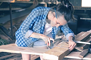 Smiling woman in a home workshop measuring tape measure a wooden Board before sawing, carpentry