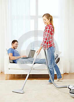 Smiling woman with hoover and man with laptop