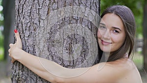 Smiling woman hugs a tree smiling, life joy, love nature, environment protection