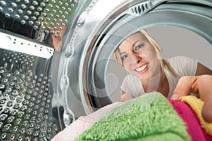 Smiling Woman Inserting Clothes In Washing Machine photo