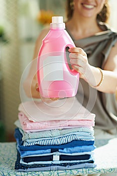 Smiling woman with ironing board, clothes and softener