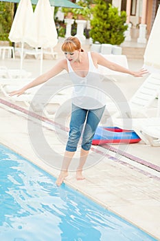 Smiling woman in jeans nearby pool