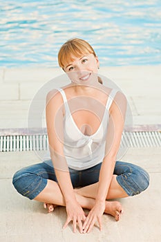 Mujer sonriente en vaqueros cerca piscina 