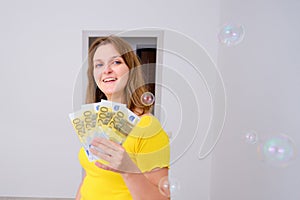 Smiling woman with keys to the apartment and the euros in their hands. Money for repair, furniture and decoration of the apartment