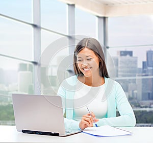 Smiling woman with laptop and notebook