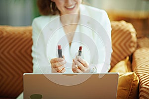 Smiling woman with laptop and two lipsticks vlogging photo