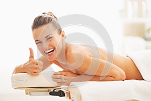 Donna sorridente dire bugie sul massaggio tavolo un visualizzato pollice in su 