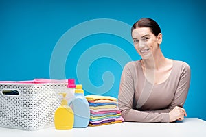 Smiling woman leaning against table with laundry