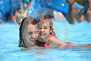 Smiling woman and little girl bathes in pool photo