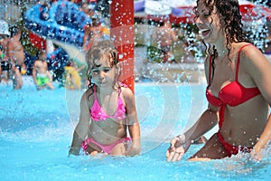 Smiling woman and little girl bathes in pool
