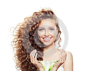 Smiling woman with long curly hair isolated on white. Beautiful model with clear skin and flowers in hands portrait