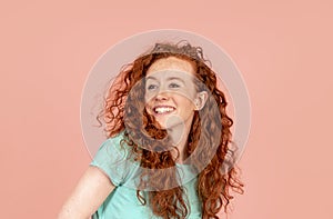 a smiling woman with long red hair in green t-shirt on pink background