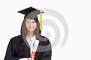 A smiling woman looking at the camera while dressed in her graduation gown