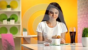 Smiling woman looking at disposable bowl with crispy fried chicken, fast food