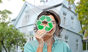Smiling woman looking through green recycling sign