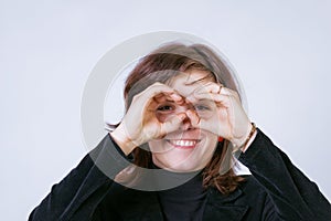 Smiling woman looks through her hands as if through binoculars