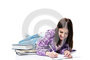 Smiling woman lying on the floor and writing in notebook