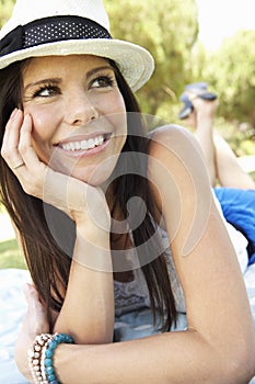 Smiling Woman Lying On Grass Wearing Sun Hat