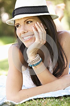 Smiling Woman Lying On Grass Wearing Sun Hat