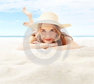 Smiling woman lying on sand beach look in camera wear sun straw hat for sun protection her skin face. Concept of summer beach