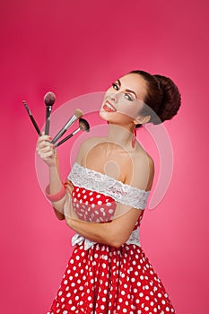 Smiling Woman with makeup brushes. She is standing