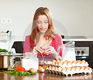 Smiling woman making dough in kitchen