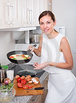 Smiling woman making omelet