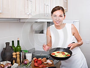 Smiling woman making omelet