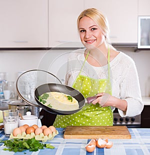 Smiling woman making omlet