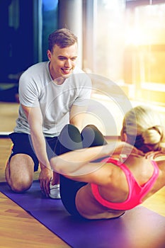 Smiling woman with male trainer exercising in gym